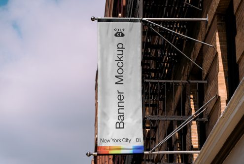 Outdoor vertical banner mockup hanging on a building facade with fire escape, clear sky background, urban design presentation.